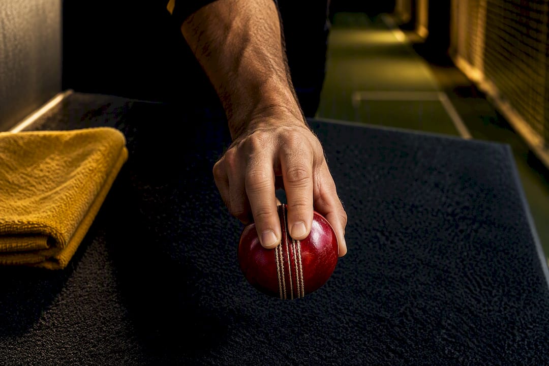 Hands demonstrating upright cricket ball seam grip