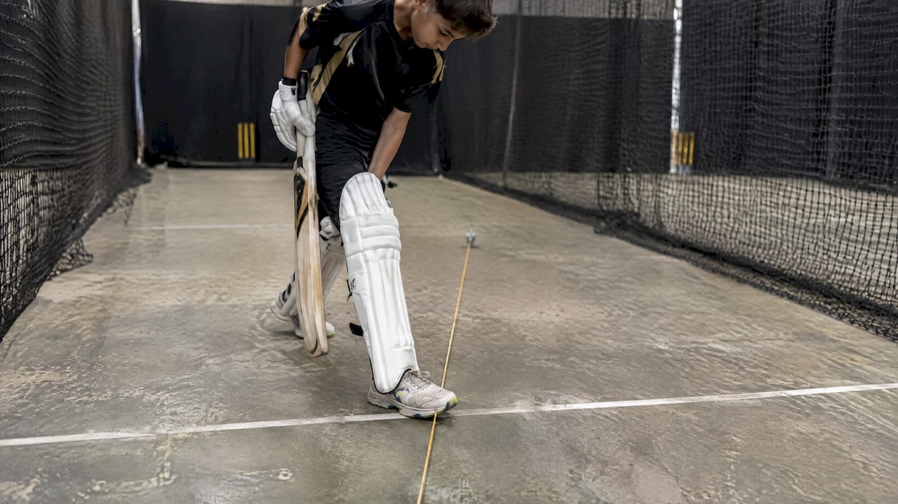 Fix Your Timing: Five Indoor Batting Timing Drills for 4–8 Week Gains Junior batter checking toe placement beside alignment string